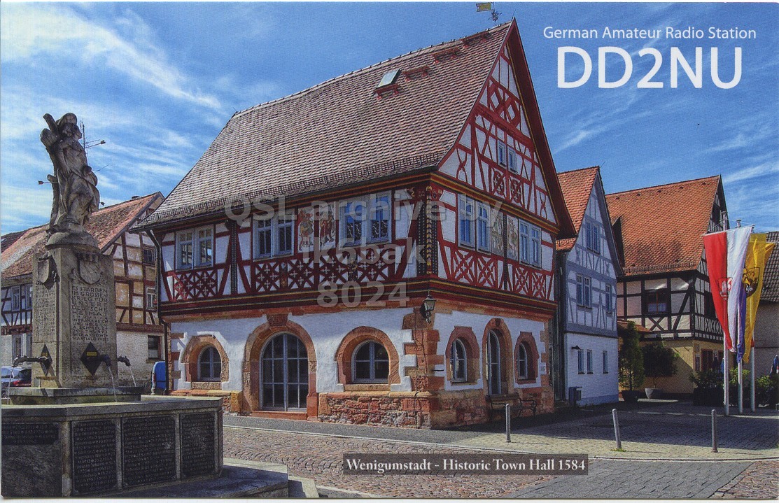 Front QSL card, of DD2NU to IK6BAK, February 26, 2023, CW mode. The QSL image contains the following objects: Monastery, City, Villa, Gothic Arch, Neighborhood. And contains this text: German Amateur Radio Station DD2NU 8024 Wenigumstadt-Historic Town Hall 1584.