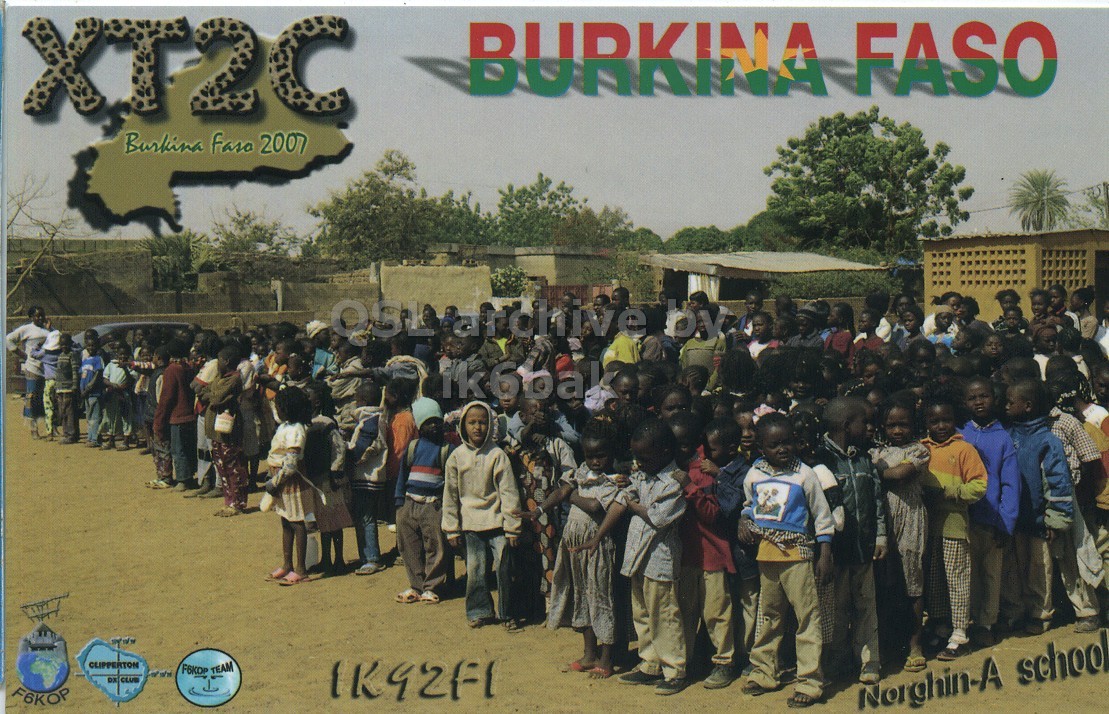 Front QSL card, of XT2C to IK6CQC, January 10, 2007, SSB mode. The QSL image contains the following objects: People, Person, Advertisement, Poster, Outdoors. And contains this text: XT2C BURKINA FASO Burkina Faso 2007 ik6bak CLIPPERTON F6KOP Norghin-A school XT2C BURKINA FASO Burkina Faso 2007 ik6bak CLIPPERTON F6KOP TEAM CLUB F6KOP Norghin-A school.